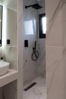 a bathroom with white marble walls and a sink at NERO SEASCAPE SUITES in Fanari