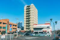 Un edificio alto con coches aparcados en un estacionamiento. en Kuretake-Inn Kakegawa, en Kakegawa
