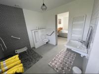 ein Bad mit einer Dusche, einem WC und einem Bett in der Unterkunft Gîte Le Rhodo in Thil-Manneville