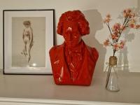 a red statue sitting on a shelf next to a vase with flowers at maison PING ,en face des arènes in Béziers