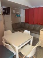 a living room with a table and chairs and a couch at MOBIL-HOME NEUF 6 PERSONNES réservation du samedi au samedi en juillet et août in Urt