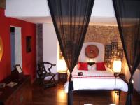 a bedroom with a white bed with red pillows at Le Prieuré des Sources in La Répara