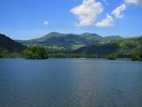 a large lake with trees and mountains in the background at Maison de Varennes in Chambon-sur-Lac