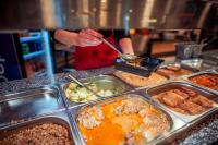 Una persona está sirviendo comida en un buffet. en Hotel Centrum Malbork, en Malbork
