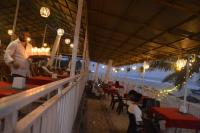 um homem em pé em um restaurante na praia em Anthy’s Guesthouse and Restaurant em Benaulim