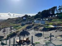 a beach with straw umbrellas and chairs on the sand at Recondito Lodge in Pichilemu