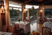 Un restaurante con mesas y sillas y un gran ventanal. en Hotel Estalagem St. Hubertus, en Gramado