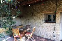 a patio with a table and chairs next to a stone wall at Gite des amis Domaine de Mas Caron in Caromb