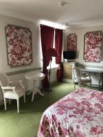 a bedroom with a bed and a table and chairs at LE CABOUILLET in LʼIsle-Adam