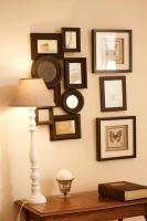 a table with a lamp and framed pictures on a wall at Gîte de la corgette in Saint-Romain