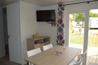 a dining room with a table and a television on a wall at Mobil home neuf en Bretagne sud in Guérande