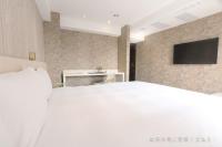 a bedroom with a white bed and a tv on a brick wall at Talmud Hotel Yizhong in Taichung