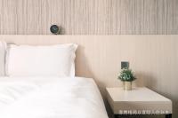 a bedroom with a white bed and a table with a plant at Talmud Hotel Yizhong in Taichung