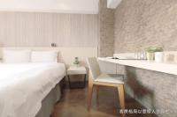 a bedroom with a bed and a desk with a chair at Talmud Hotel Yizhong in Taichung