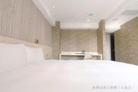 a bedroom with a white bed and a desk at Talmud Hotel Yizhong in Taichung