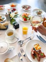 a table with plates of food and a person holding a glass of wine at Hôtel Royal in Évian-les-Bains