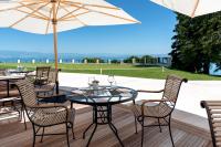 a table and chairs on a deck with an umbrella at Hôtel Royal in Évian-les-Bains