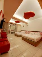 a bedroom with two beds and a red chair at Happy Heart B&amp;B in Taitung City