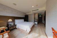 a bedroom with a large white bed and a desk at Shihzuwan Hotel – Kaohsiung Station in Kaohsiung
