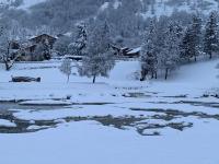 a snow covered field with trees and a river at Chaleureux studio plein sud en Tarentaise ! in Bozel