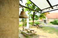 Eine Glocke hängt neben einer Bank im Hof in der Unterkunft La ferme de Roquedure in Montfaucon