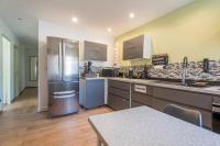 a large kitchen with stainless steel appliances and wooden floors at Chambre 26m - Salon et kitchenette privé - WIFI in Woippy