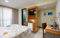 a bedroom with a bed and a desk with a computer at Hotel Santorini in Vila Velha