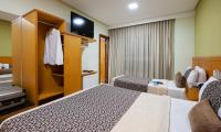 a hotel room with two beds and a tv at Hotel Santorini in Vila Velha