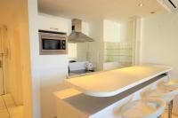 a kitchen with a counter and two stools in it at Palais Miramar - Suite White Jardin - 20m Plage in Cannes