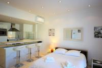 a bedroom with a white bed and a kitchen at Palais Miramar - Suite White Jardin - 20m Plage in Cannes
