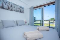 Un dormitorio con una cama blanca con una ventana grande. en Beach View - Vue Océan, en Buarcos