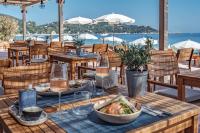 a wooden table with a bowl of food and wine glasses at Surplage Hotel Cavalière in Le Lavandou
