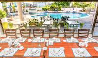 a dining table with chairs and a pool in the background at Hotel Cristina Suites in Puerto La Cruz