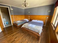 プンタ・アレナスにあるHostal Ochenの木製の床の部屋にベッドが2つあります