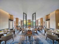 een eetkamer met tafels en stoelen en ramen bij Doubletree By Hilton Lingshui Hot Spring in Lingshui