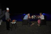un grupo de personas sentadas en una mesa por la noche en Mountain Club Resort Munnar, en Chinnakanal