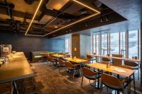 een restaurant met houten tafels en stoelen en ramen bij Fenix Furano in Furano