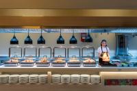 Eine Frau, die hinter einer Theke in einer Küche mit Essen steht. in der Unterkunft Kaya Izmir Thermal & Convention in Izmir