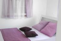 a bed with purple pillows in a room with a window at Maison de 2 chambres avec vue sur la mer jardin amenage et wifi a Vieux Habitants a 2 km de la plage in Vieux-Habitants