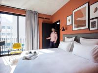 a man standing in a hotel room with a bed at Deskopolitan House in Paris