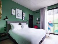 a bedroom with a large white bed and a green wall at Deskopolitan House in Paris