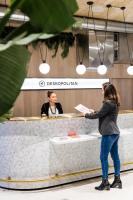 a woman standing in front of a counter holding a paper at Deskopolitan House in Paris