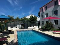 a swimming pool with chairs and an umbrella next to a building at Kyriad Montpellier Aéroport - Gare Sud de France in Mauguio