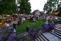 Milzkalne庄园住宅酒店的一群人坐在公园里，周围环绕着鲜花。