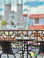 eine Terrasse mit Tischen und Stühlen vor einer Kirche in der Unterkunft Wayfarer Guest House Jonker Street Melaka By Heystay Management in Malakka