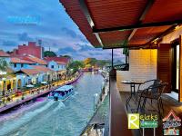 ein Boot, das einen Fluss hinunter in einer Stadt fährt in der Unterkunft Wayfarer Guest House Jonker Street Melaka By Heystay Management in Malakka
