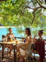 a group of people sitting at a table near the water at Haadson Resort & Koh Raham in Haad Son