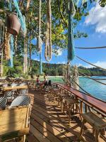 two people sitting on a wooden deck next to the water at Haadson Resort & Koh Raham in Haad Son