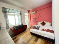 a bedroom with a bed and a red chair at Rihchun Homestay in Hengchun South Gate