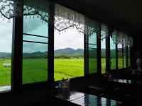 een kamer met ramen die uitkijken op een groen veld bij Doi Samoe Dao Hostel in Nan